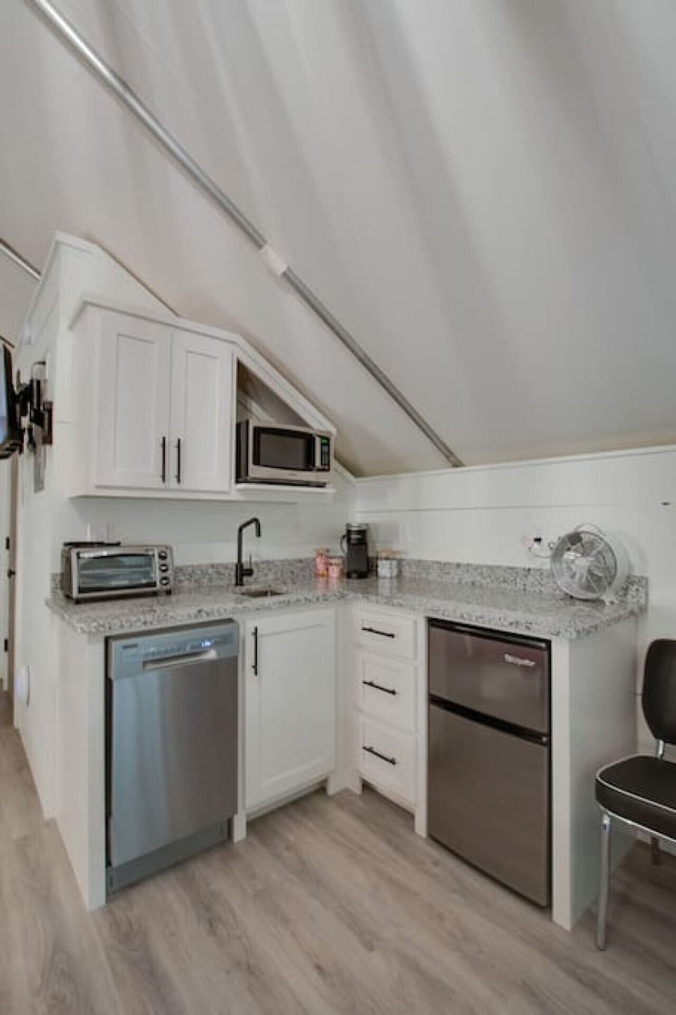 Well-equipped glamping tent with a modern kitchenette, including a dishwasher, fridge, and coffee maker, perfect for enjoying the comforts of home in a nature-filled setting.