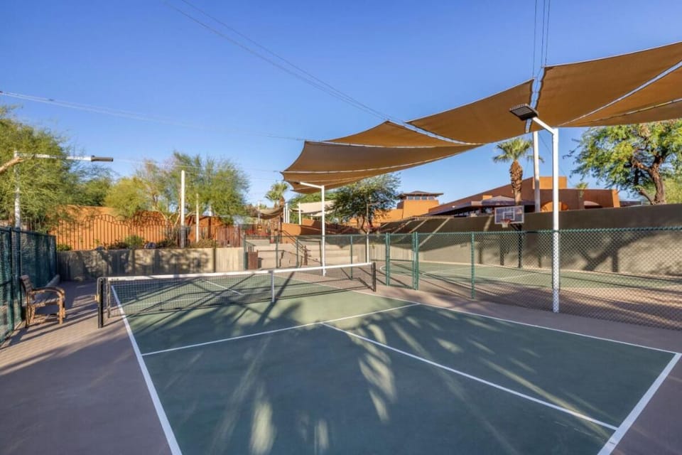 Play a spirited match on shaded courts under desert skies.