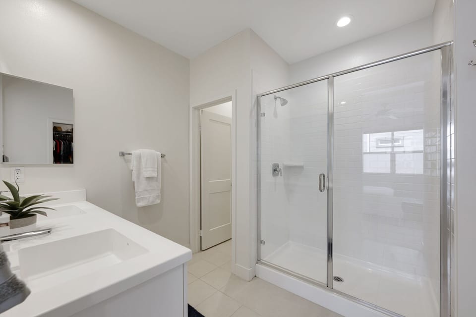 En suite walk in shower, dual sinks, and walk in closet in primary bath