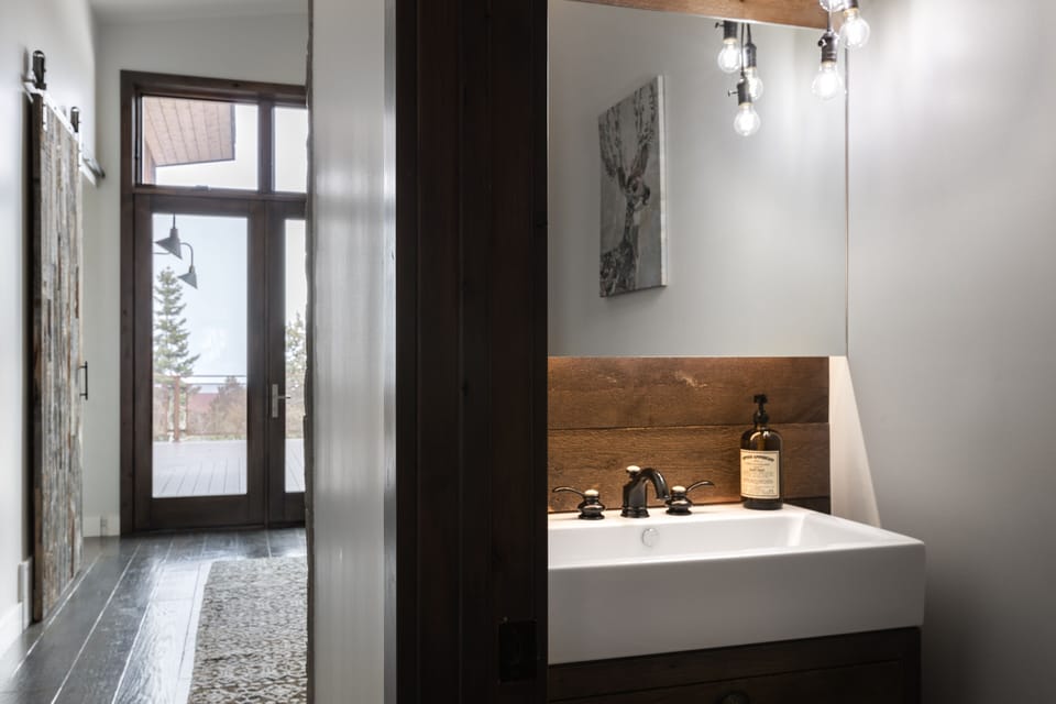 - Half bathroom with wood accents and modern sink  
- Warm lighting and rustic details create charm  
- Conveniently located near entry for easy access