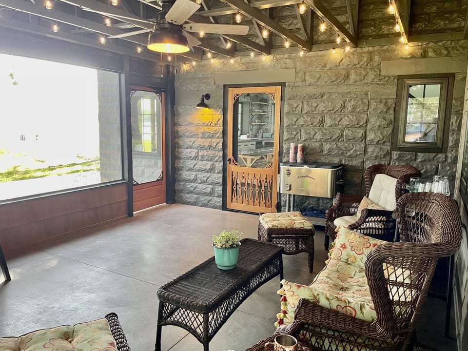 screened porch with lots of seating, a large drink cooler, fan, and lake views.