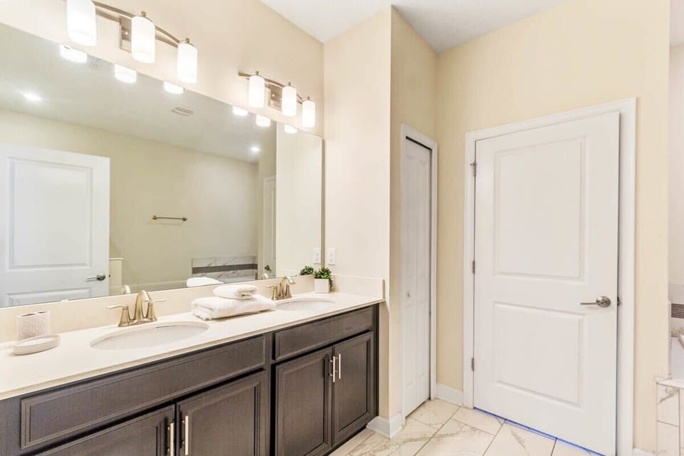 The spacious full bathroom combines comfort and convenience with a double vanity, shower, bright lighting, and an inviting atmosphere perfect for refreshing after a day of vacation fun.