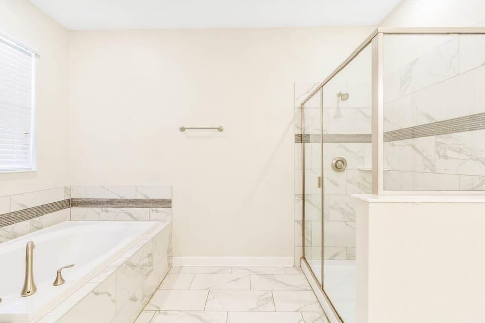 The spacious full bathroom combines comfort and convenience with a double vanity, shower, bright lighting, and an inviting atmosphere perfect for refreshing after a day of vacation fun.