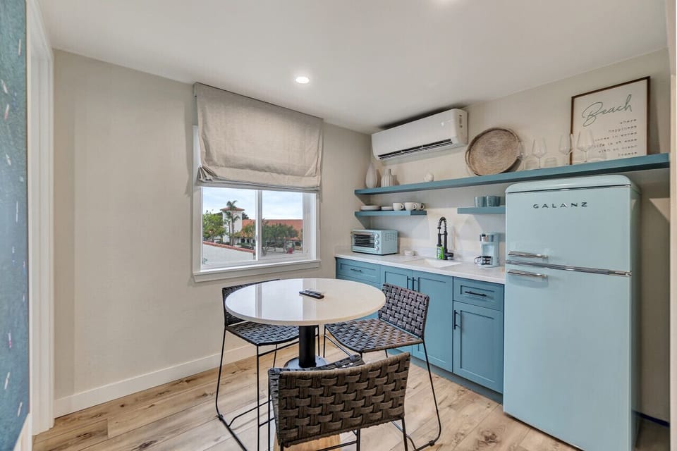 Charming kitchenette w/ retro-style fridge, open shelving & a sunny dining nook by the window
