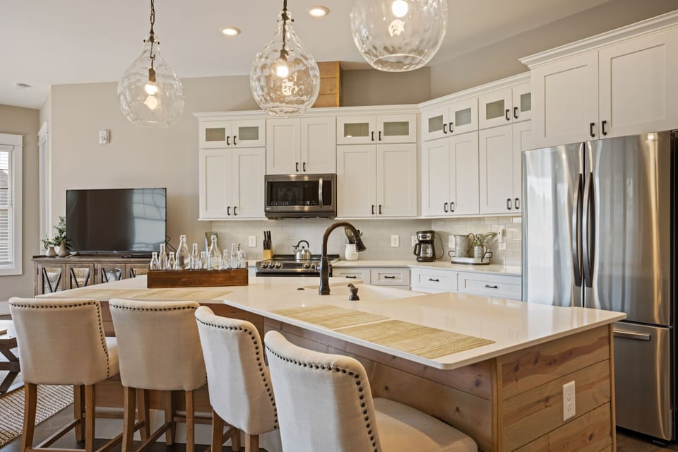 Sleek open kitchen w/ stainless steel appliances & granite island for 4 dining.