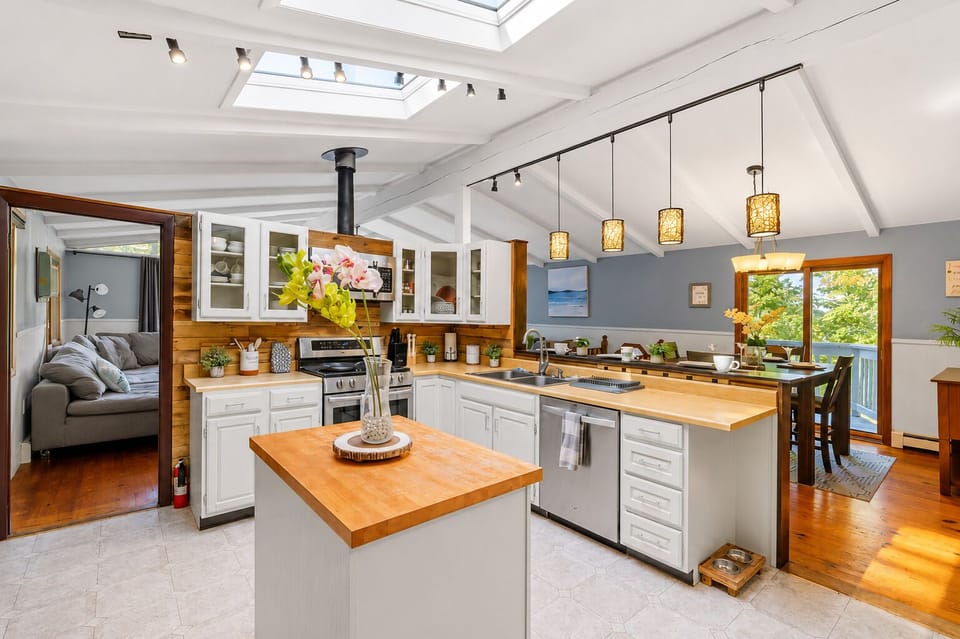 Kitchen with butcher-block island, skylights, and a wood stove beyond

