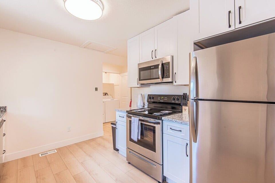 Kitchen with stainless steel appliances, white cabinetry, and modern cooking essentials.
