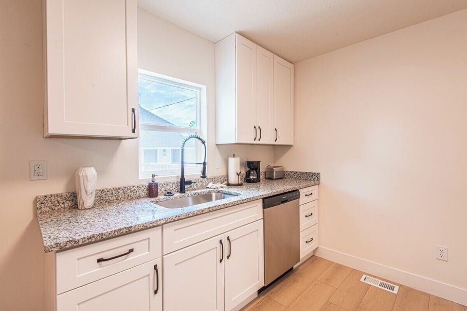 Kitchen with granite countertop, white cabinetry, and stainless steel appliances.