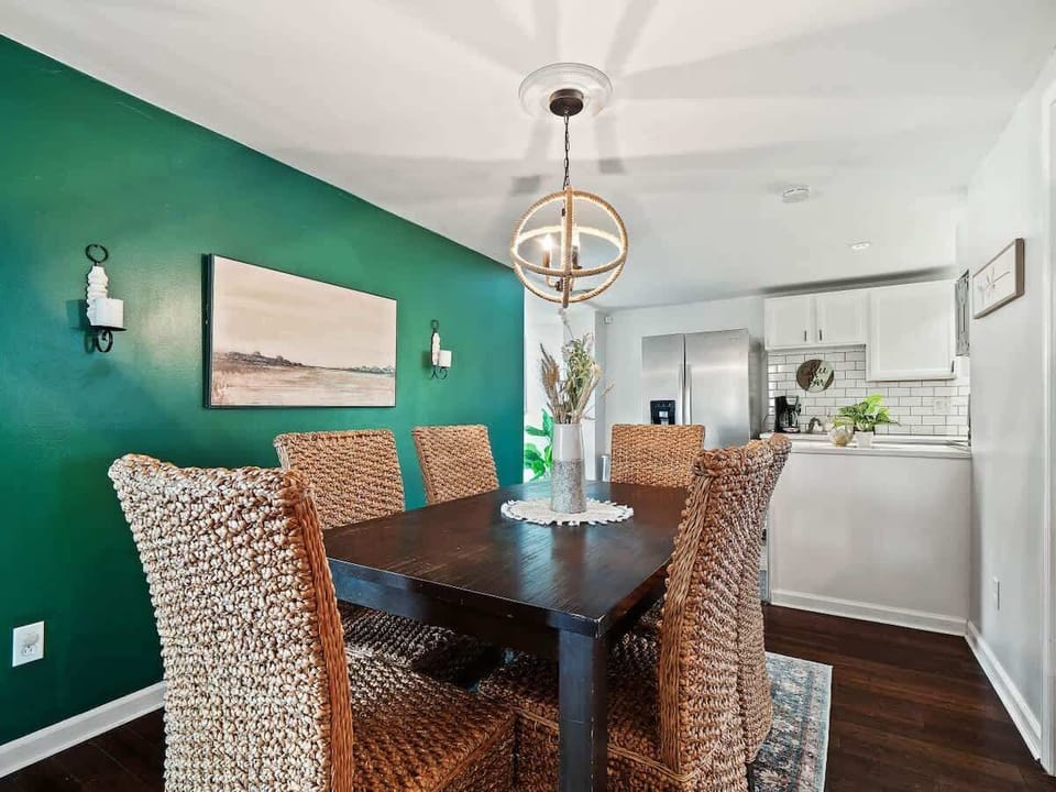 Gather for meals or game nights in this stylish dining area featuring a bold green accent wall, woven chairs, and warm lighting ️ The open layout flows seamlessly into the modern kitchen for easy entertaining!