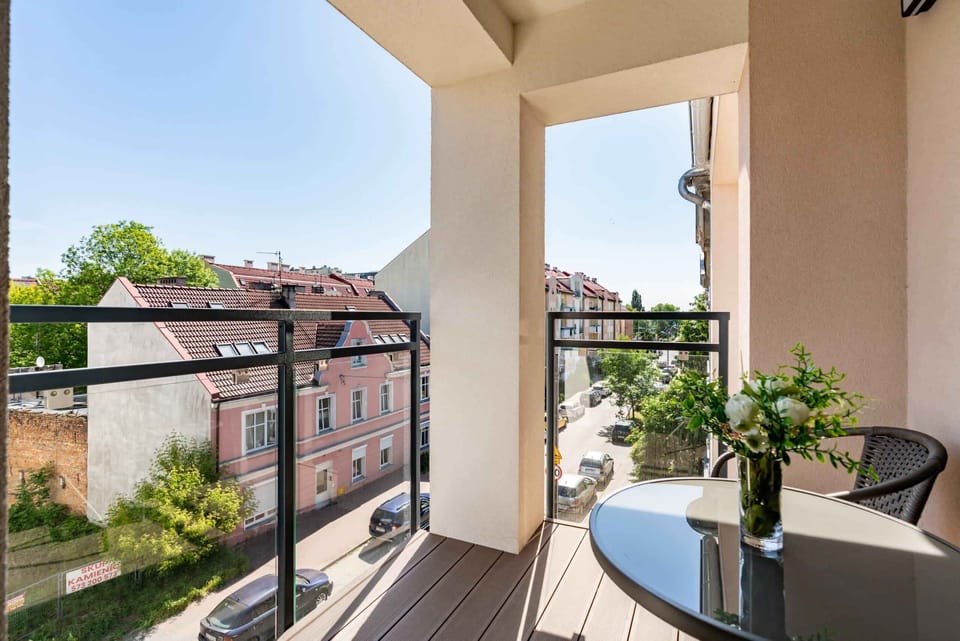 A spacious balcony with outdoor seating and a view of the surrounding urban landscape.