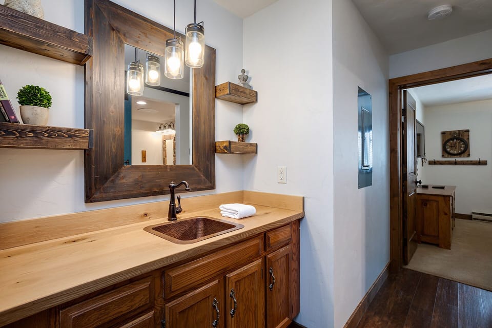 Rustic charm meets modern comfort in your bathroom, featuring rich wood cabinetry, mason jar lighting, and thoughtful touches that create a warm, welcoming retreat.