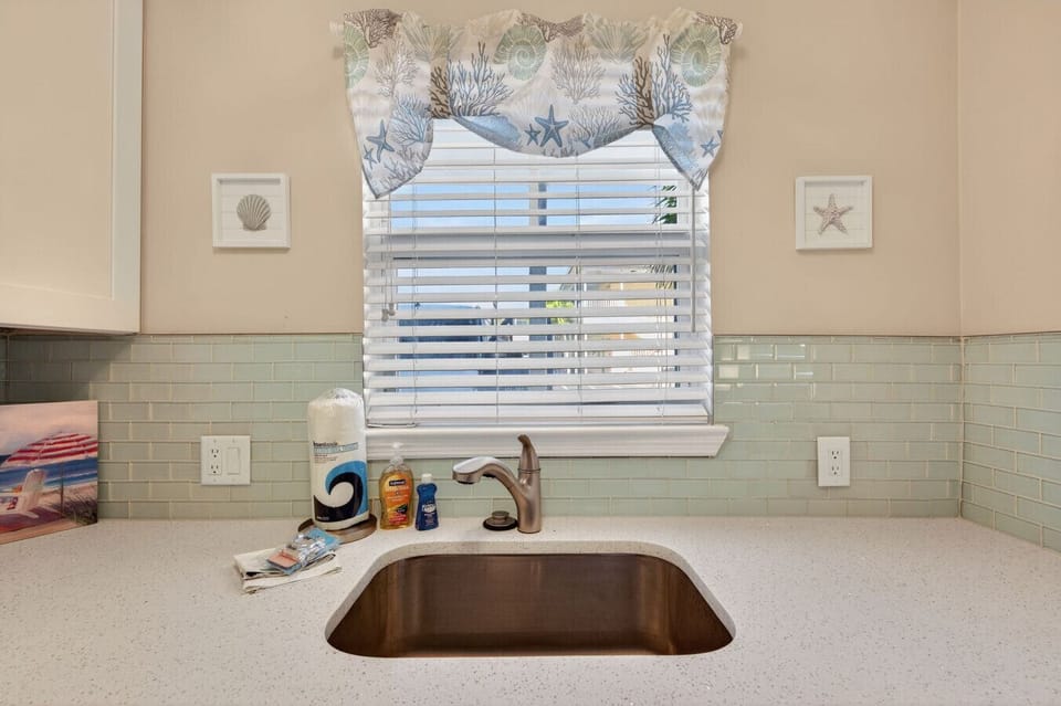Clean kitchen sink area w/ tiled backsplash & charming beach-inspired details.