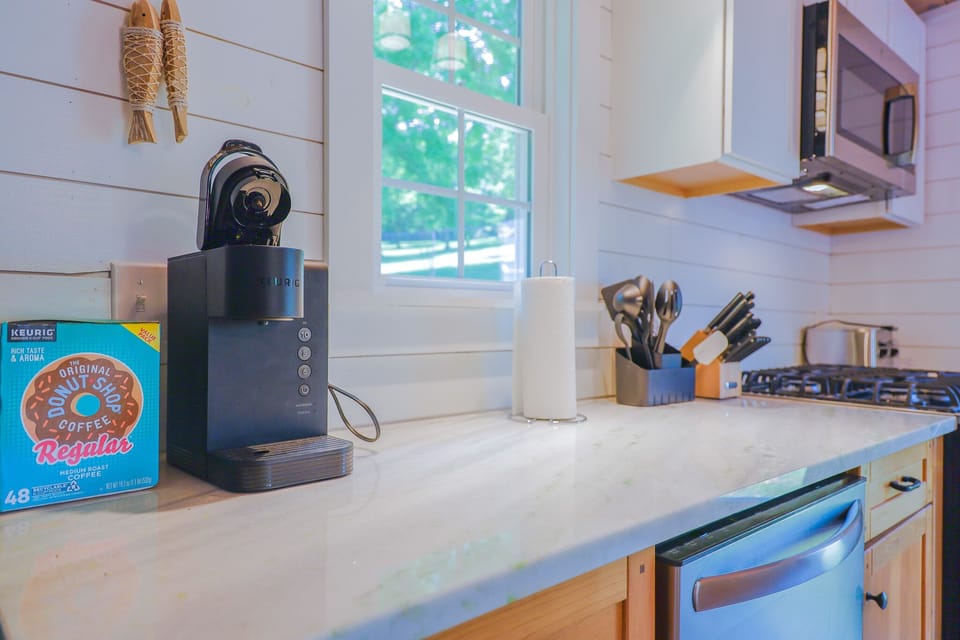 Modern kitchen counter with coffee maker, gas stove, and natural light from a bright window.