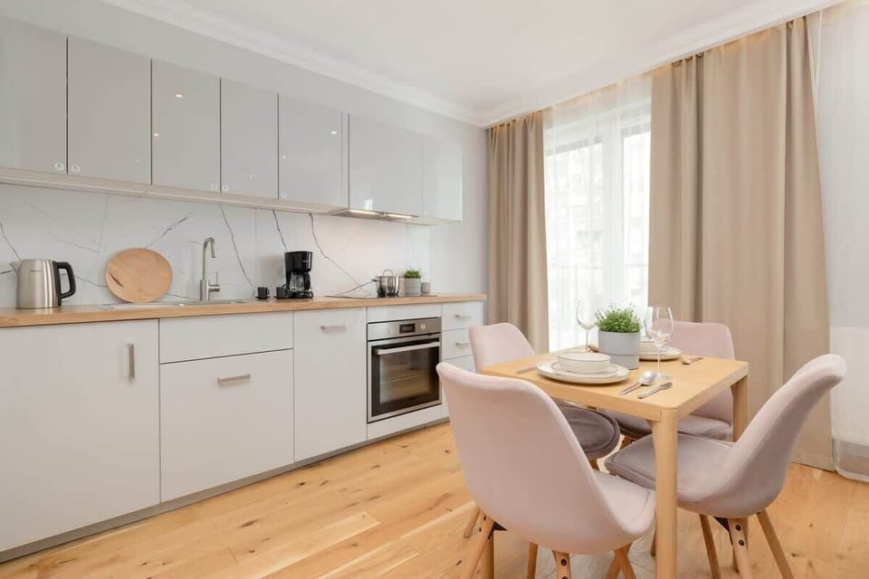 An open-concept kitchen with white cabinets, modern appliances, and a dining table with elegant chairs.