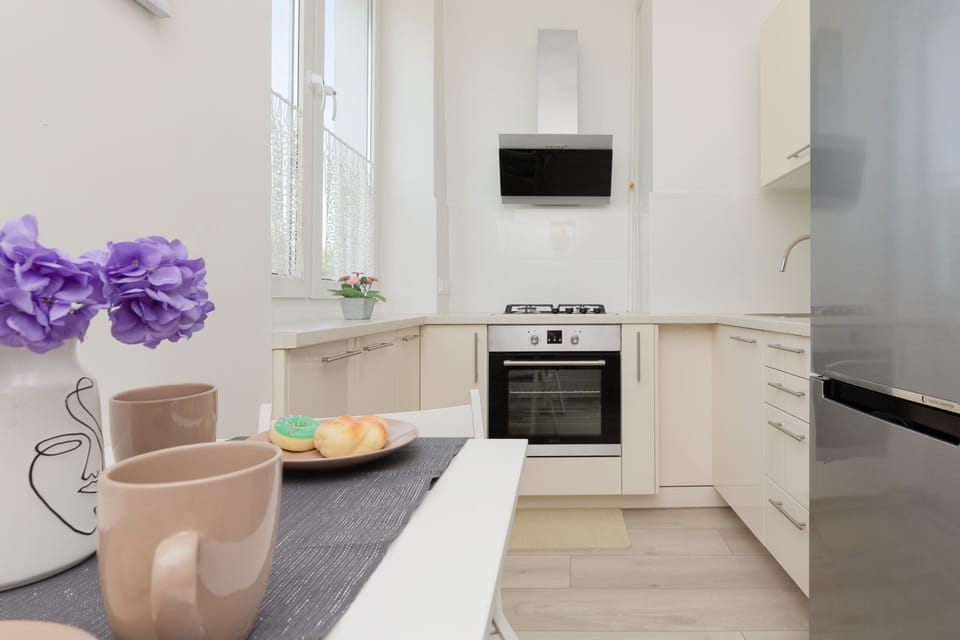 A well-lit dining area with a small table set for two, placed next to a fully equipped kitchen.