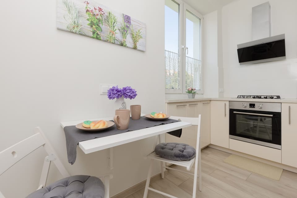 A well-lit dining area with a small table set for two, placed next to a fully equipped kitchen.