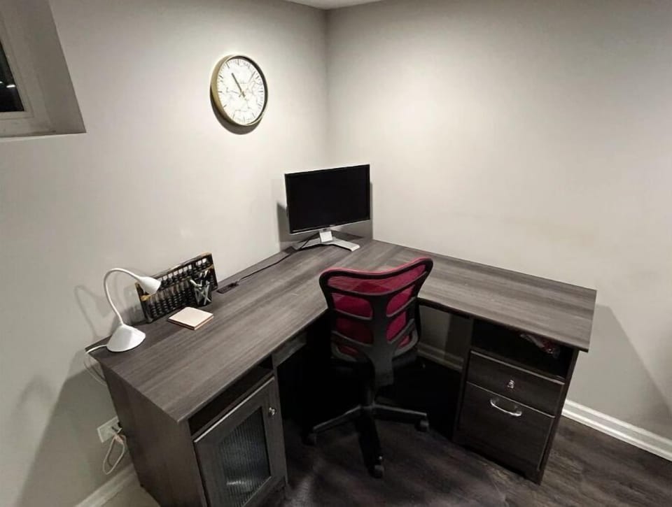 Basement workspace with monitor, desk lamp, and office supplies.