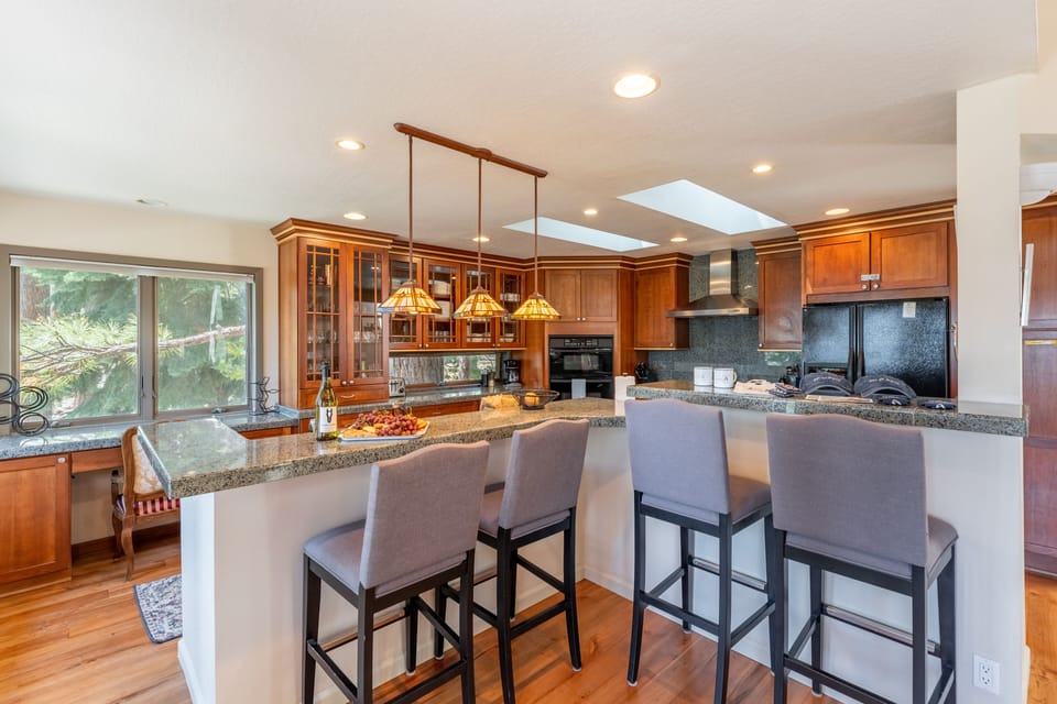 Fully-equipped kitchen with modern appliances, a workspace, and barstool seating at the counter.