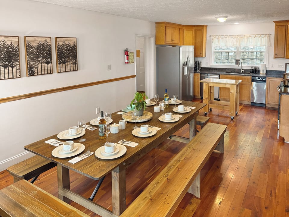 This charming kitchen features a small butcher block island perfect for meal prep, flowing into a spacious dining area with a large table—ideal for family meals, game nights, or gathering with friends after a day of mountain adventures.