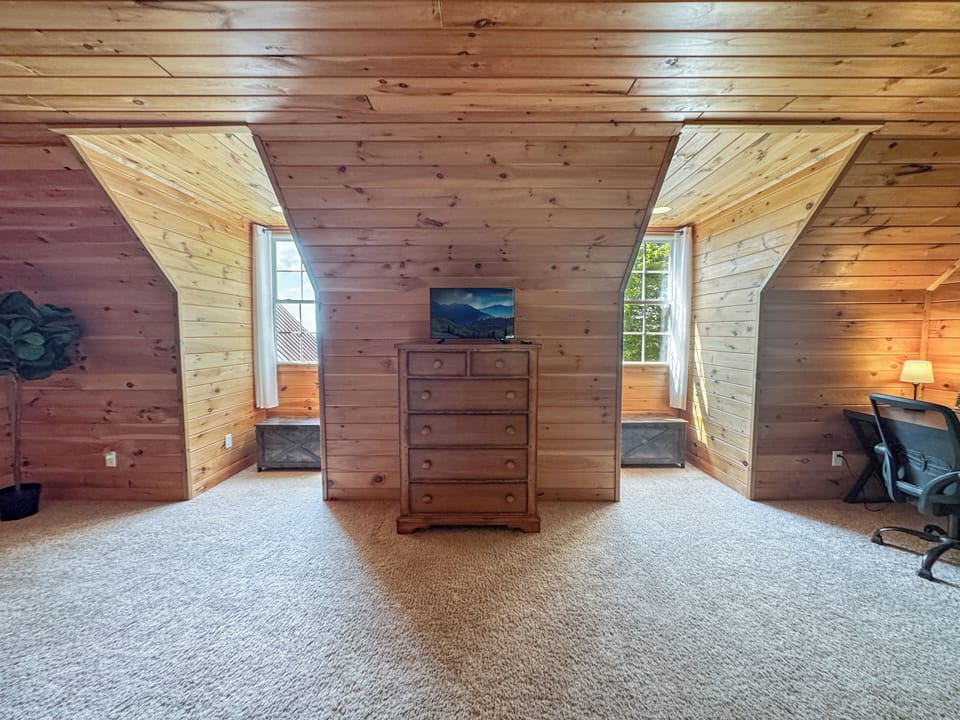 Enjoy comfort and privacy in this charming queen bedroom featuring a private bathroom and a dedicated workspace with a desk and chair. Ideal for couples or remote workers looking to relax and stay productive during their mountain getaway.