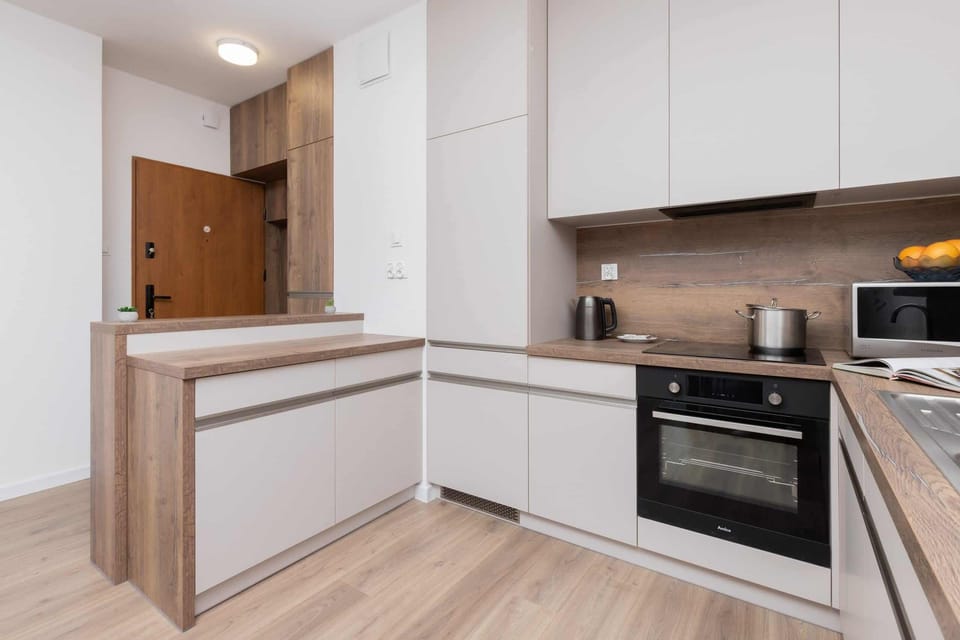 A sleek kitchen with white cabinets, wooden countertops, and modern appliances.