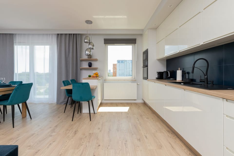 A fully equipped kitchen with sleek white cabinets and a contrasting black backsplash.