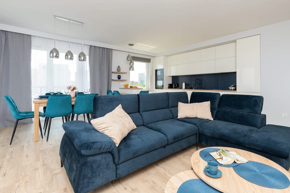 A bright and open living area featuring a large blue sectional sofa, a coffee table, and modern decor.