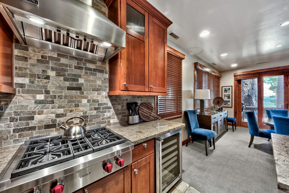 Stone tile backsplash highlights the stainless steel range and granite counters in the kitchen.
