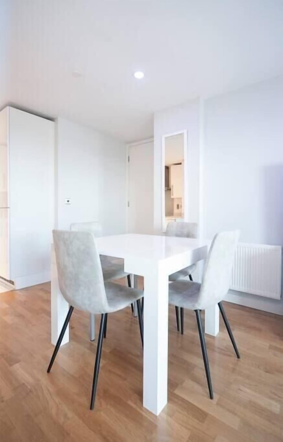 A modern living room on the 12th floor features a 60-inch TV, a dining table with four chairs, and access to a balcony with stunning city views. Two electric reclined sofas provide comfort and a sound system offer entertainment.