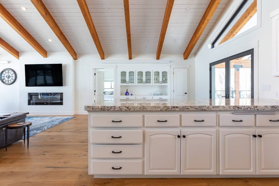 Kitchen peninsula with a view of the great room of the fireplace and large TV