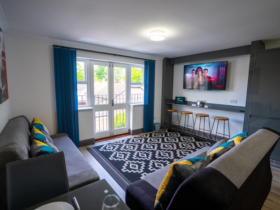 Relax on the plush sofa adorned with modern throw pillows, adding a pop of color and texture to the room. The flat-screen TV provides entertainment at your fingertips, perfect for movie nights or catching up on your favorite shows.