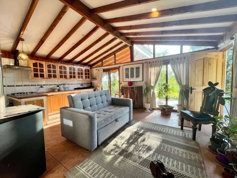 Spacious living room w/ exposed wood beams, cozy seating & natural light pouring in