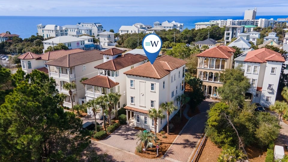 Elegant coastal retreat with red tile roofs and tropical landscaping, perfectly positioned between lush greenery and sparkling blue waters.