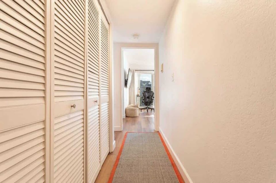 This hallway connects the Primary bedroom at one end to the two other bedrooms at the other end. Behind the folding doors are a full size washer and dryer for your use.

