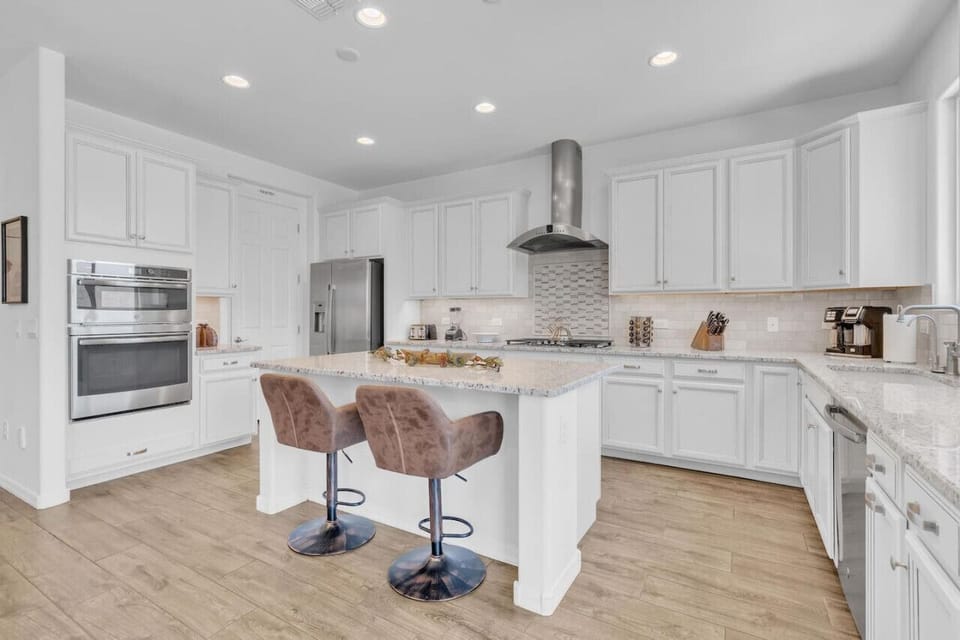 Primary kitchen with gas stove, double oven, walk-in pantry, granite countertops, and large island