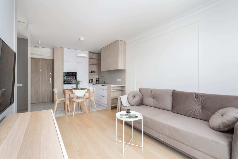Living room with a comfortable sofa bed, TV and kitchenette with dining area.