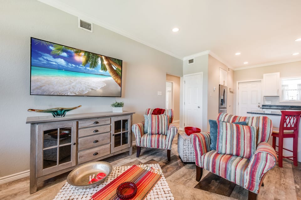 Relax in your vibrant living space with colorful striped chairs, large flat-screen TV, and coastal charm flowing throughout.