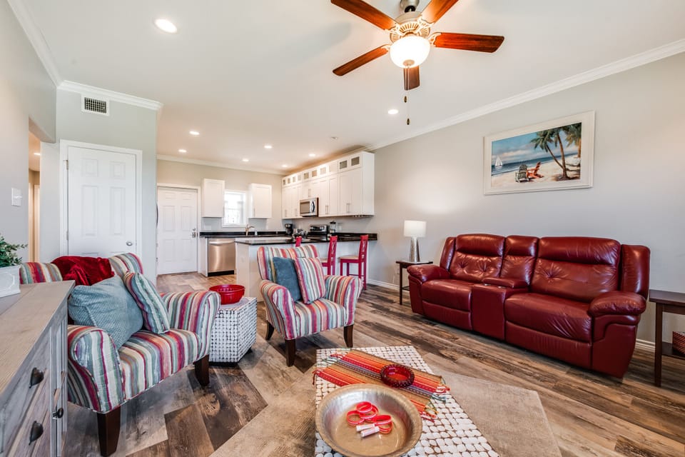 Relax in your spacious open-concept living area featuring comfortable seating, modern kitchen, and cheerful coastal touches that make you feel right at home.