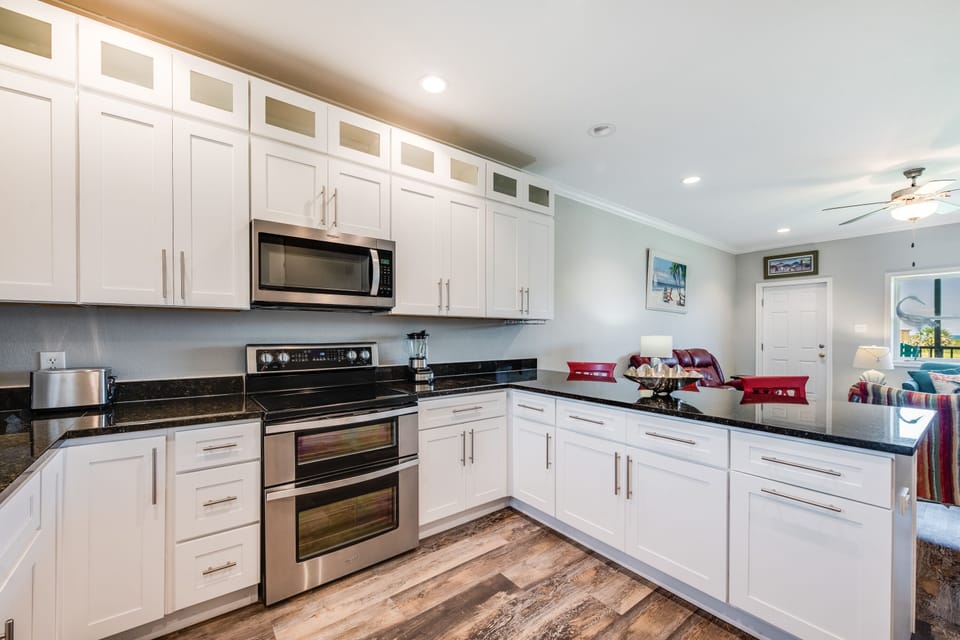 Prepare delicious meals in your spacious kitchen featuring gleaming granite countertops, pristine white cabinetry, and modern stainless steel appliances.