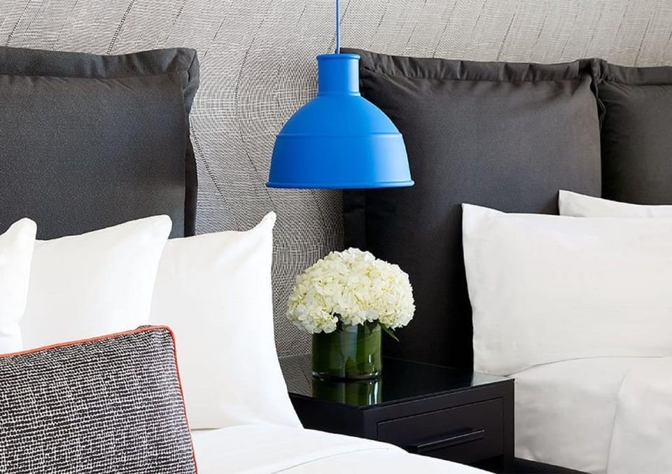 Recharge beside soft pillows and warm, modern bedside lighting.