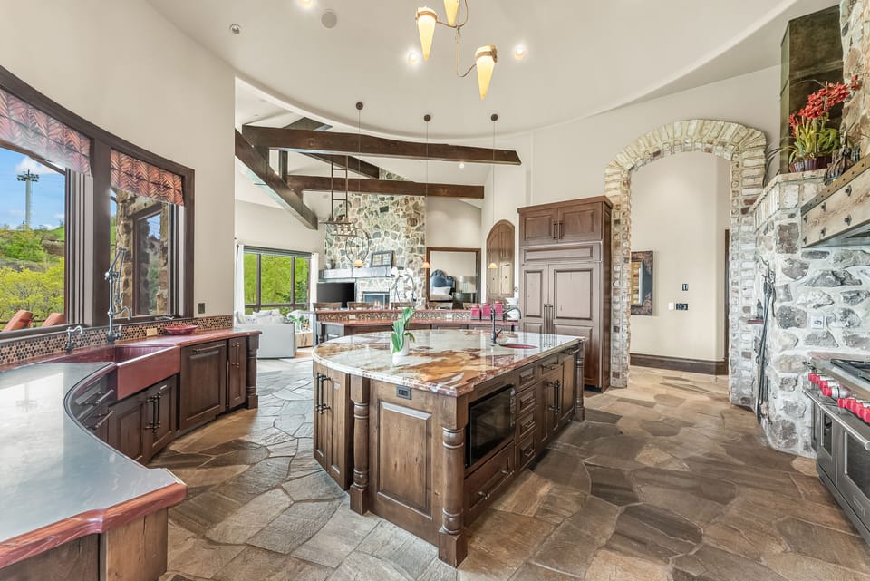 - Expansive kitchen with stone floors and wood cabinetry  
- Large island perfect for cooking and gathering  
- Open design flowing into living area with views