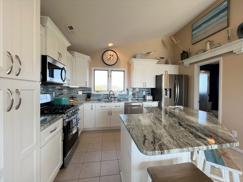 Your gourmet kitchen awaits with granite countertops, stainless steel appliances, and ocean-inspired backsplash - perfect for creating memorable vacation meals together.