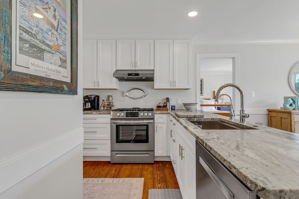 Upgraded custom kitchen with white cabinetry, stainless appliances, granite