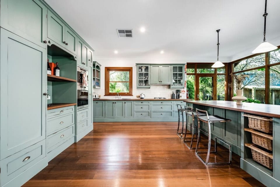 This bright coastal nook features a tall wooden table with matching stools, perfectly positioned by large windows that frame serene ocean views and lush pine trees—ideal for relaxed seaside dining or morning coffee.         You said:  make a short descrip
