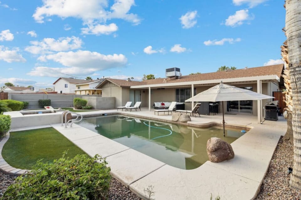 Private backyard with pool, lounge chairs, and covered patio