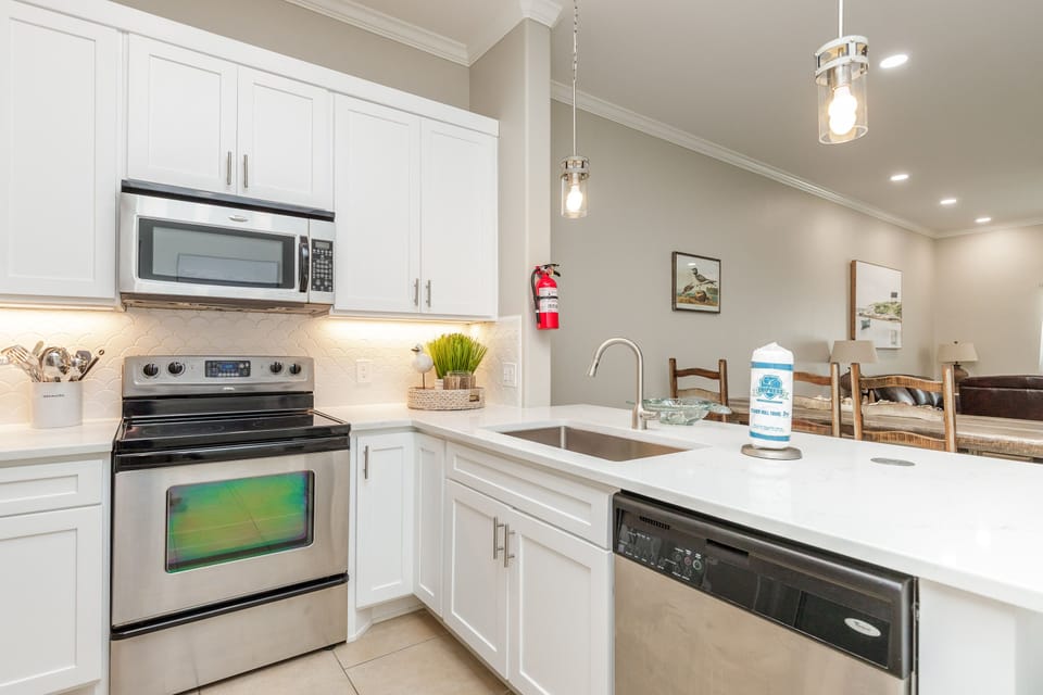 Cook your favorite meals in this bright, fully-equipped kitchen with modern appliances and elegant white cabinetry designed for your comfort.