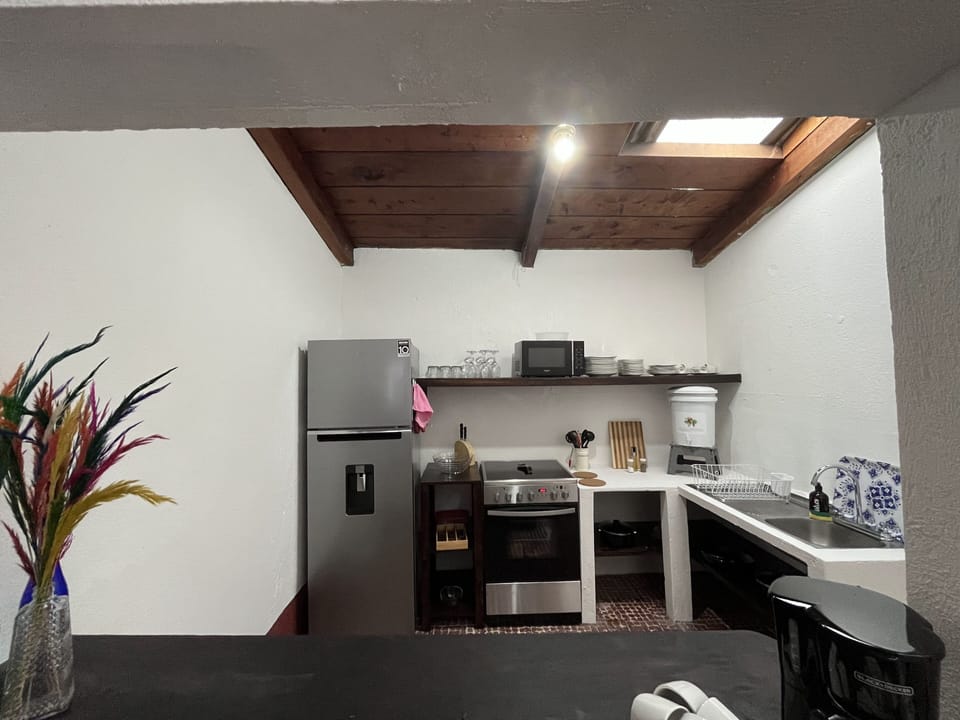 There is a refrigerator, stove, microwave, pots, pans and dishes