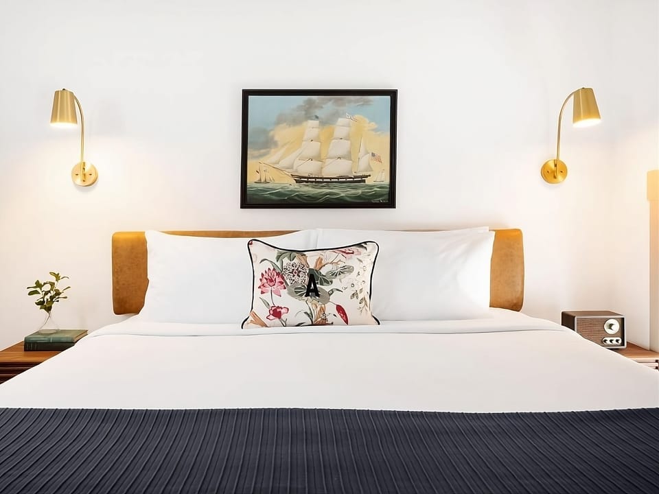 Sink into crisp linens beneath warm lights and artwork.