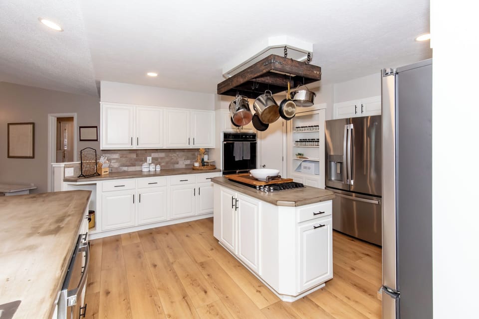 Your gourmet kitchen awaits with gleaming stainless steel appliances, warm wood floors, and a rustic pot rack for effortless home cooking.