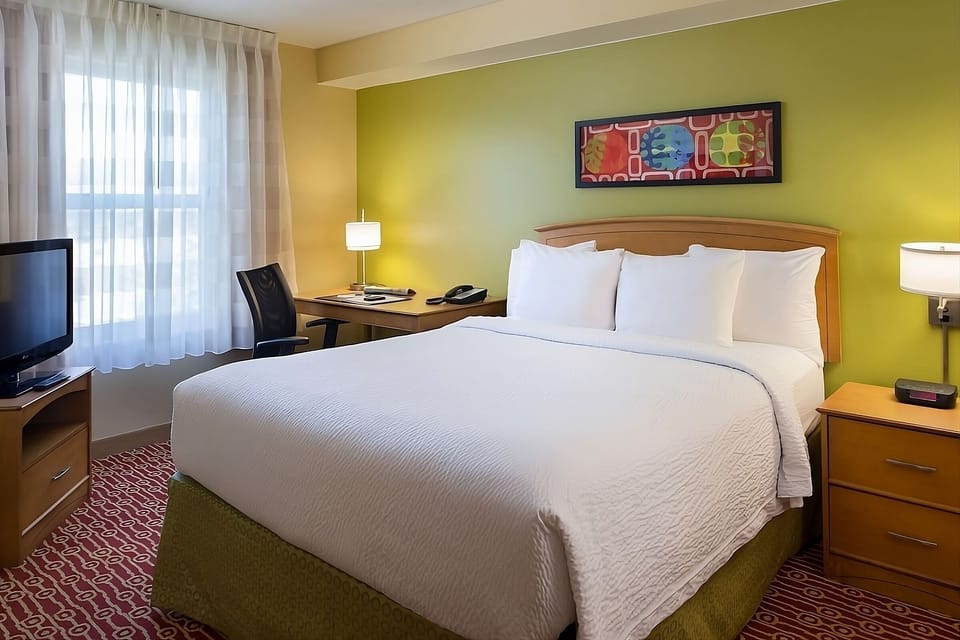 Stretch out on the plush bed in a sunlit room.